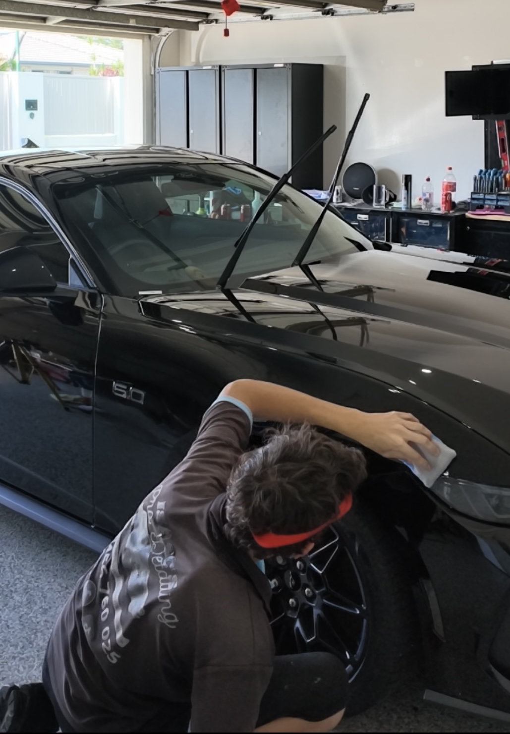Isaac polishing a black Mustang